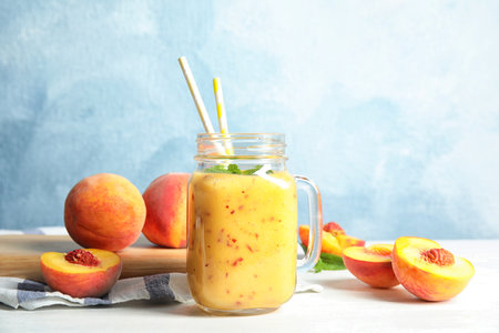 Tasty peach smoothie in mason jar on tableの写真素材