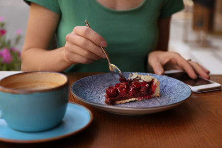 Woman eating slice of cherry cake at table, closeupの写真素材
