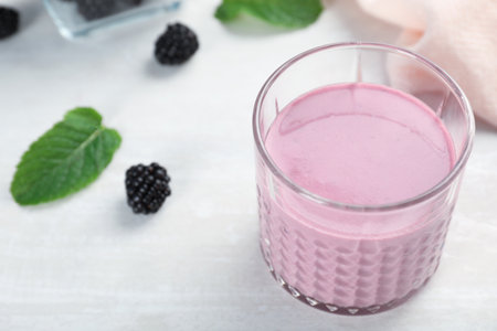 Glass with tasty blackberry yogurt smoothie on tableの写真素材