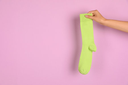 Woman holding bright sock and space for design on color backgroundの写真素材