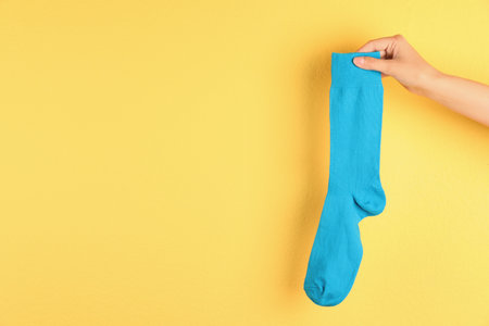 Woman holding bright sock and space for design on color backgroundの写真素材