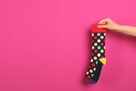 Woman holding bright sock and space for design on color backgroundの写真素材