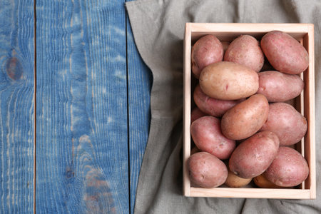 Crate with fresh ripe organic potatoes on wooden background, top viewの写真素材