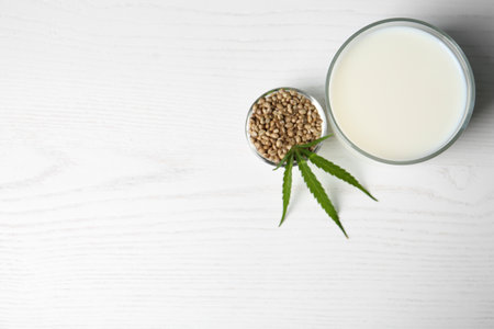 Glass of hemp milk and space for text on white wooden background, top viewの写真素材