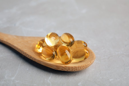 Spoon with cod liver oil pills on table, closeupの写真素材