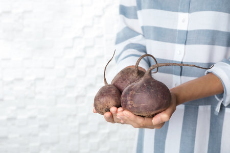 Woman holding ripe beets on light backgroundの写真素材
