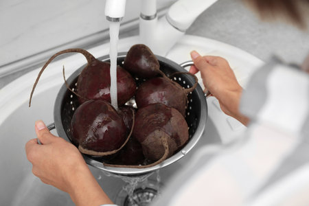 Woman washing ripe beets in kitchen sink, closeupの写真素材