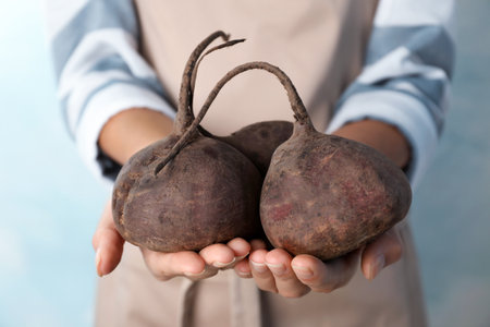 Woman holding ripe beets on light backgroundの写真素材