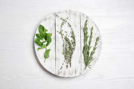 Board with rosemary, mint and thyme on wooden background, flat lay. aromatic herbsの写真素材