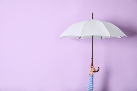 Person holding bright open umbrella on color background with space for designの写真素材