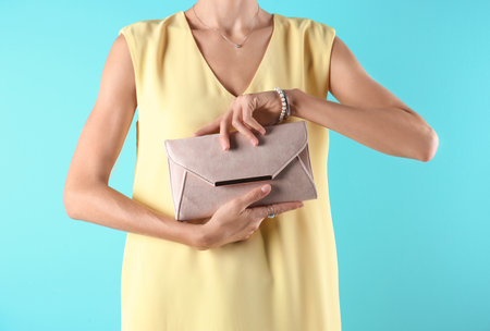 Young woman in stylish outfit with purse on color background, closeupの写真素材