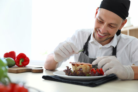 Professional chef presenting dish on table in kitchenの写真素材
