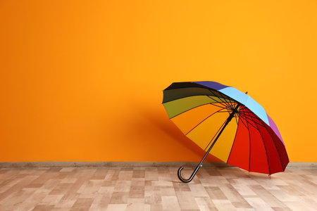 Beautiful open umbrella on floor near color wall with space for designの写真素材