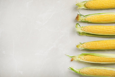 Tasty sweet corn cobs on table, top view