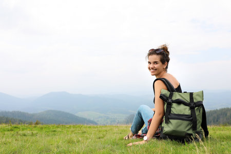 Woman with backpack in wilderness on cloudy dayの写真素材