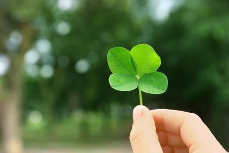 Woman holding four-leaf clover outdoors, closeupの写真素材