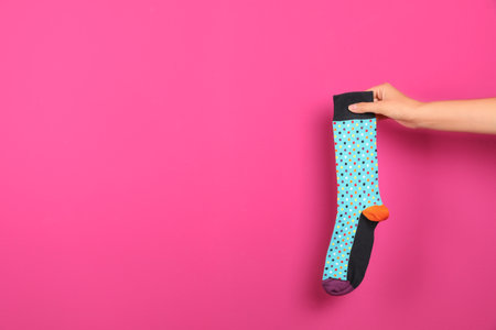 Woman holding bright sock and space for design on color backgroundの写真素材