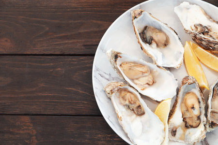Fresh oysters with cut juicy lemon and space for text on table, top viewの写真素材