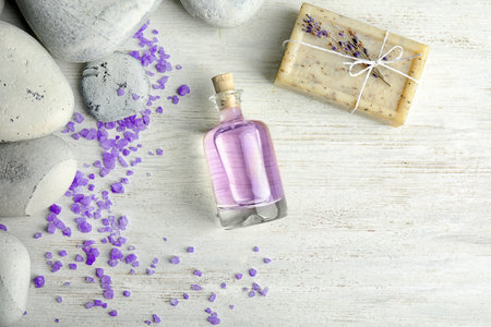 Flat lay composition with natural herbal oil, soap and lavender flowers on wooden background. Space for textの写真素材