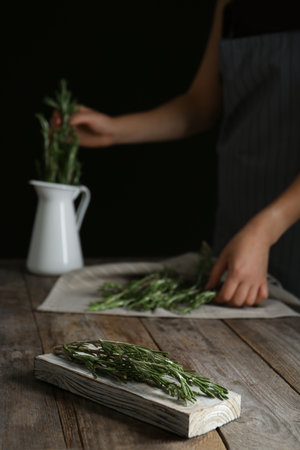 Wooden board with fresh green rosemary and woman on background. aromatic herbsの写真素材
