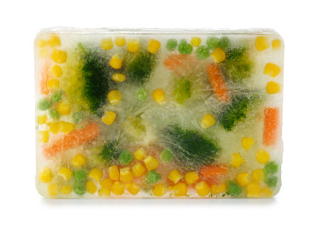 Fresh vegetables frozen in ice cube on white background