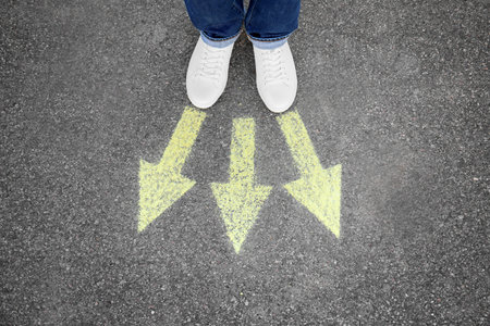 Woman standing on road near arrows marking, closeupの写真素材