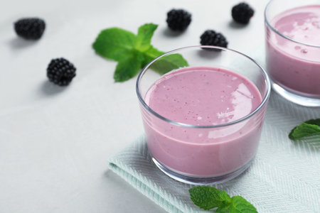 Glasses with tasty blackberry yogurt smoothies on tableの写真素材