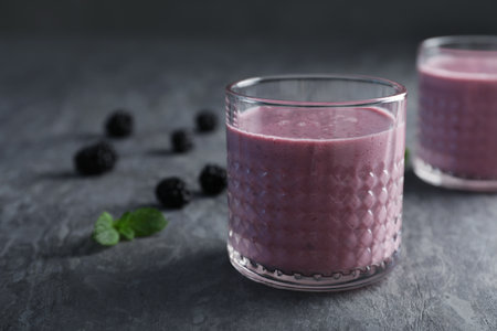 Glass with blackberry yogurt smoothie on gray tableの写真素材