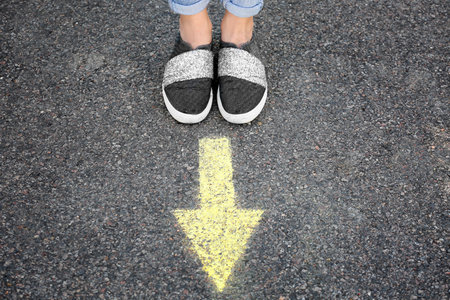 Woman standing on road near arrow marking, closeupの写真素材
