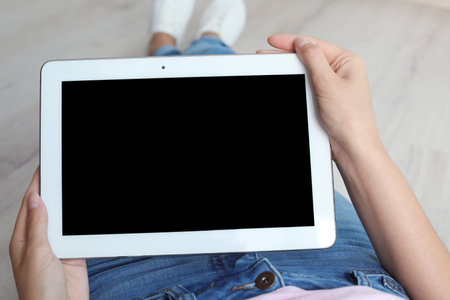 Woman holding tablet with blank screen indoors. Mockup for designの写真素材