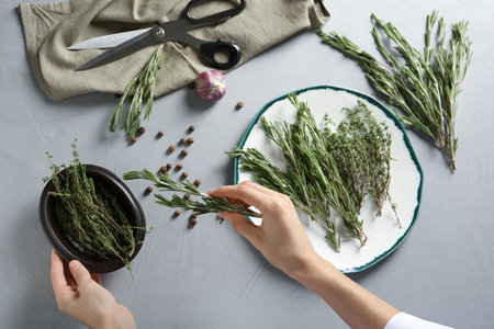 Woman with rosemary and other aromatic herbs at table, top viewの写真素材
