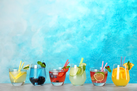 Glasses with lemonades on table against color backgroundの写真素材