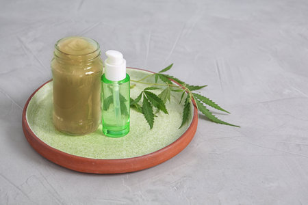 Tray with containers of hemp lotion and oil on gray table. Space for textの写真素材