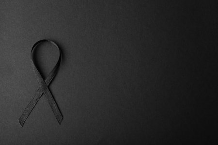 Black ribbon and space for text on dark background, top view. funeral accessoryの写真素材