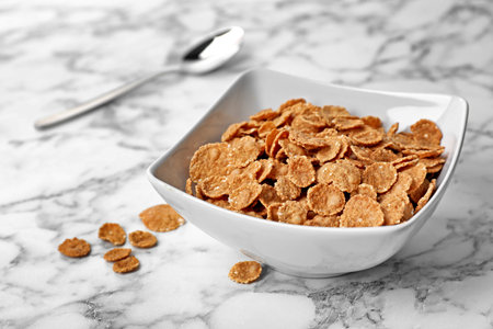 Bowl with cornflakes on marble table. Whole grain cereal for breakfastの写真素材