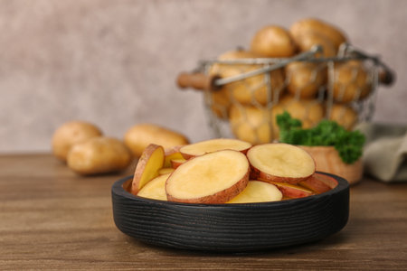 Fresh organic potatoes in dish on wooden tableの写真素材