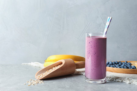 Glass with blueberry smoothie on gray tableの写真素材