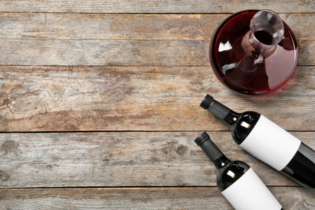 Decanter and bottles with red wine on wooden background, top viewの写真素材