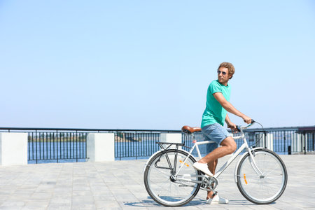 Handsome young man riding bicycle outdoors on sunny dayの写真素材