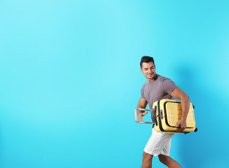 Young man with suitcase on color background. Space for textの写真素材