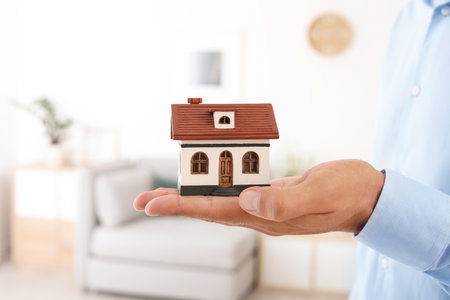 Real estate agent holding house model on blurred backgroundの写真素材
