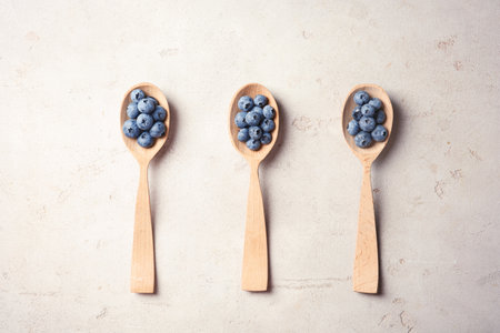 Flat lay composition with spoons and juicy blueberries on color tableの写真素材