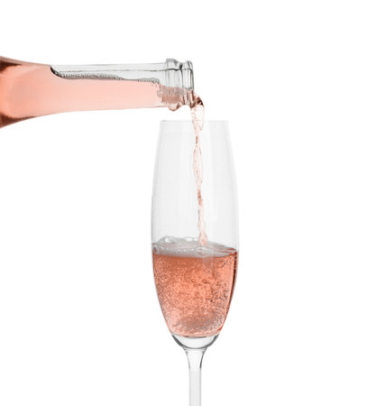 Pouring rose champagne from bottle into glass on white backgroundの写真素材