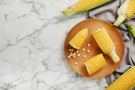 Plate with tasty sweet corn cobs on marble table, top view
