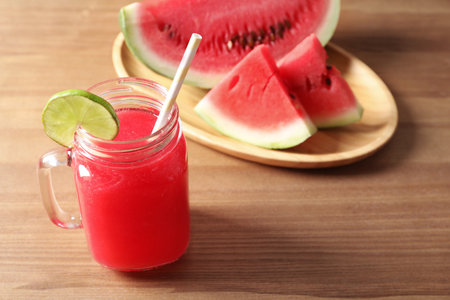 Summer watermelon drink in mason jar and sliced fruit on tableの写真素材