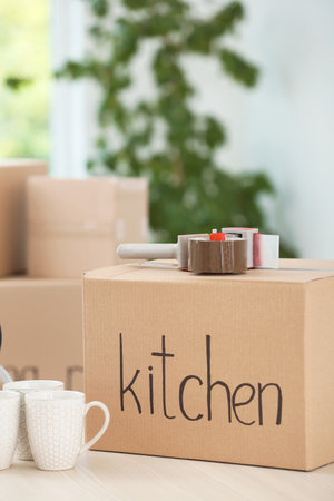 Cardboard box, cups and adhesive tape dispenser on table indoors. moving dayの写真素材