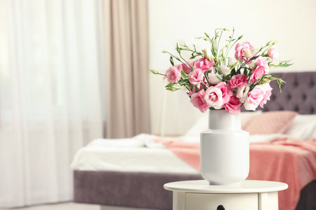 Vase with beautiful flowers on table in bedroom, space for textの写真素材