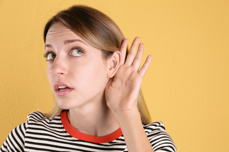Young woman with hearing problem on color backgroundの写真素材