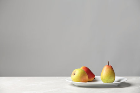 Plate with pears on table against gray background. Space for textの写真素材