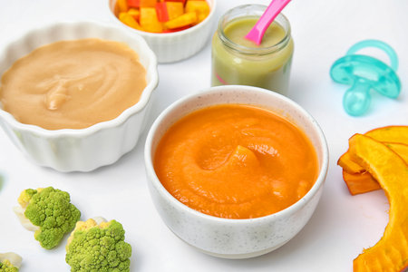 Bowls with healthy baby food on white backgroundの写真素材